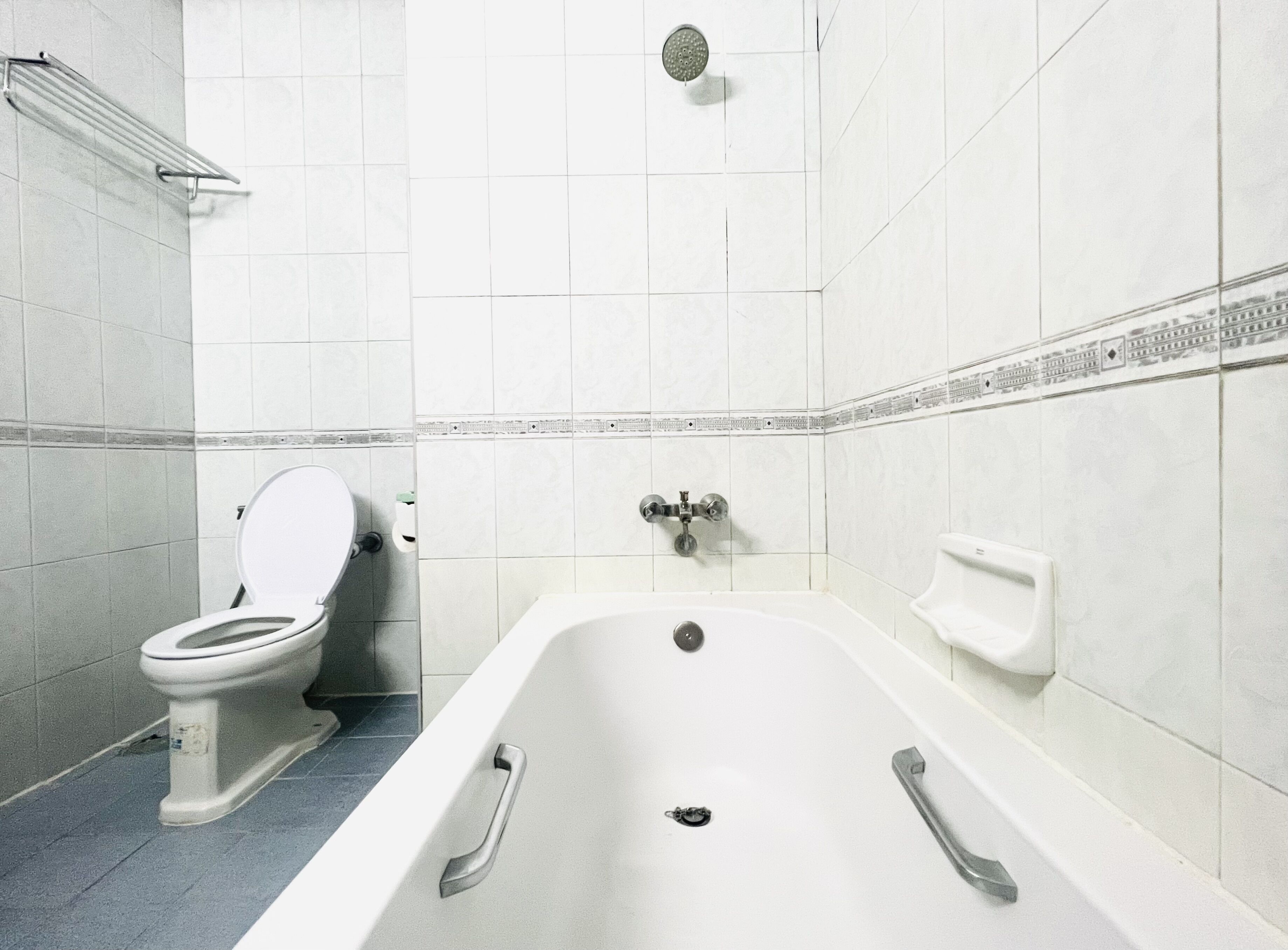 Un baño con inodoro, bañera, ducha y un perchero para toallas.