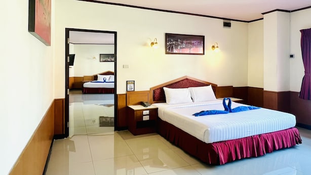 A hotel room with a large bed, bedside tables, a mirror, and a cityscape picture on the wall. - PN Mansion (Pattaya)