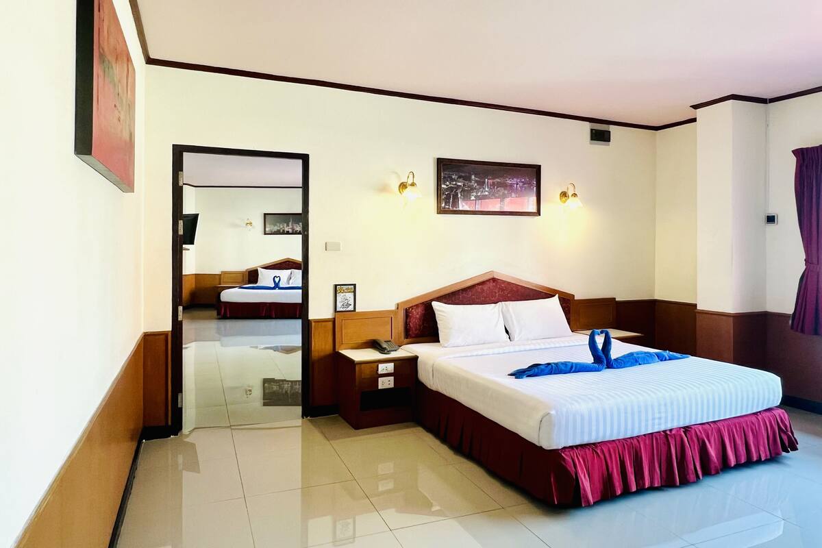 A hotel room with a large bed, bedside tables, a mirror, and a cityscape picture on the wall.