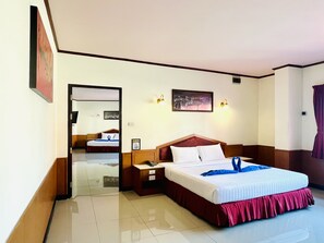 A hotel room with a large bed, bedside tables, a mirror, and a cityscape picture on the wall. - PN Mansion (Pattaya)