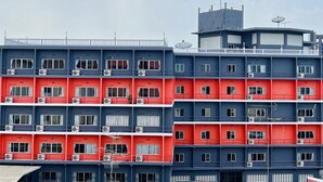 A multi-story building with alternating red and blue facades, air conditioning units, and a satellite dish on the roof. - PN Mansion (Pattaya)
