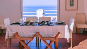 A dining table set for two with a view of the ocean.