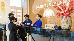 A reception desk at Sandals Island with a wooden backdrop and a sign.