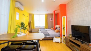 Une chambre d’hôtel de taille réduite, comprenant un lit, un téléviseur, une table à manger avec des chaises et une petite plante.
