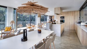 Una cocina moderna con una isla grande, armarios blancos y una lámpara colgante de fibras naturales.