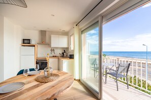 Een moderne keuken met witte kasten en een houten eettafel.