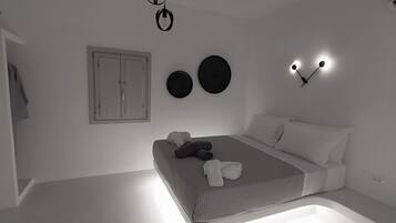 Un dormitorio moderno con cama, mesitas de noche, lámpara colgante y decoración circular en la pared.