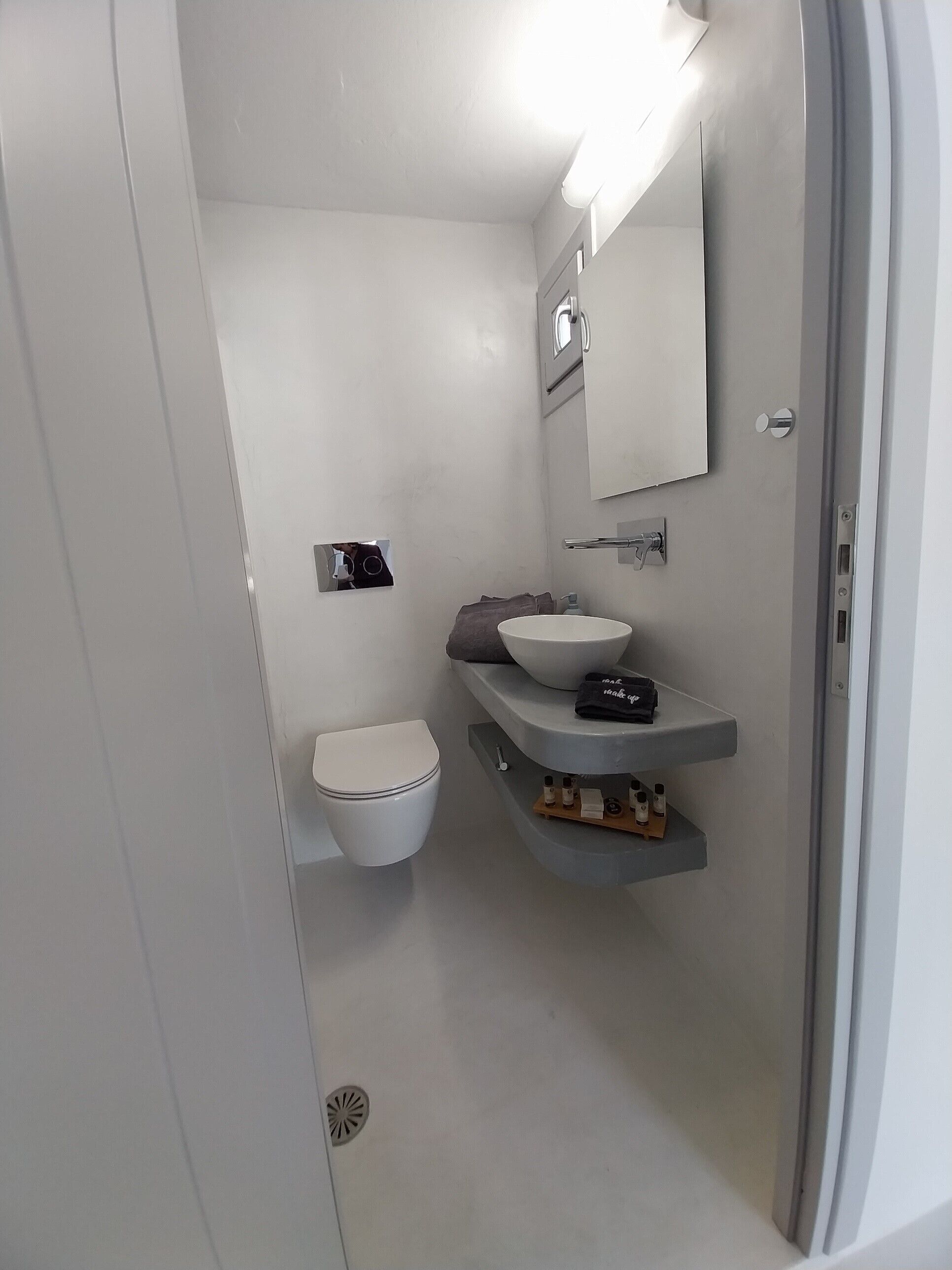 A modern bathroom with a white toilet, a white sink, and a mirror above the sink.