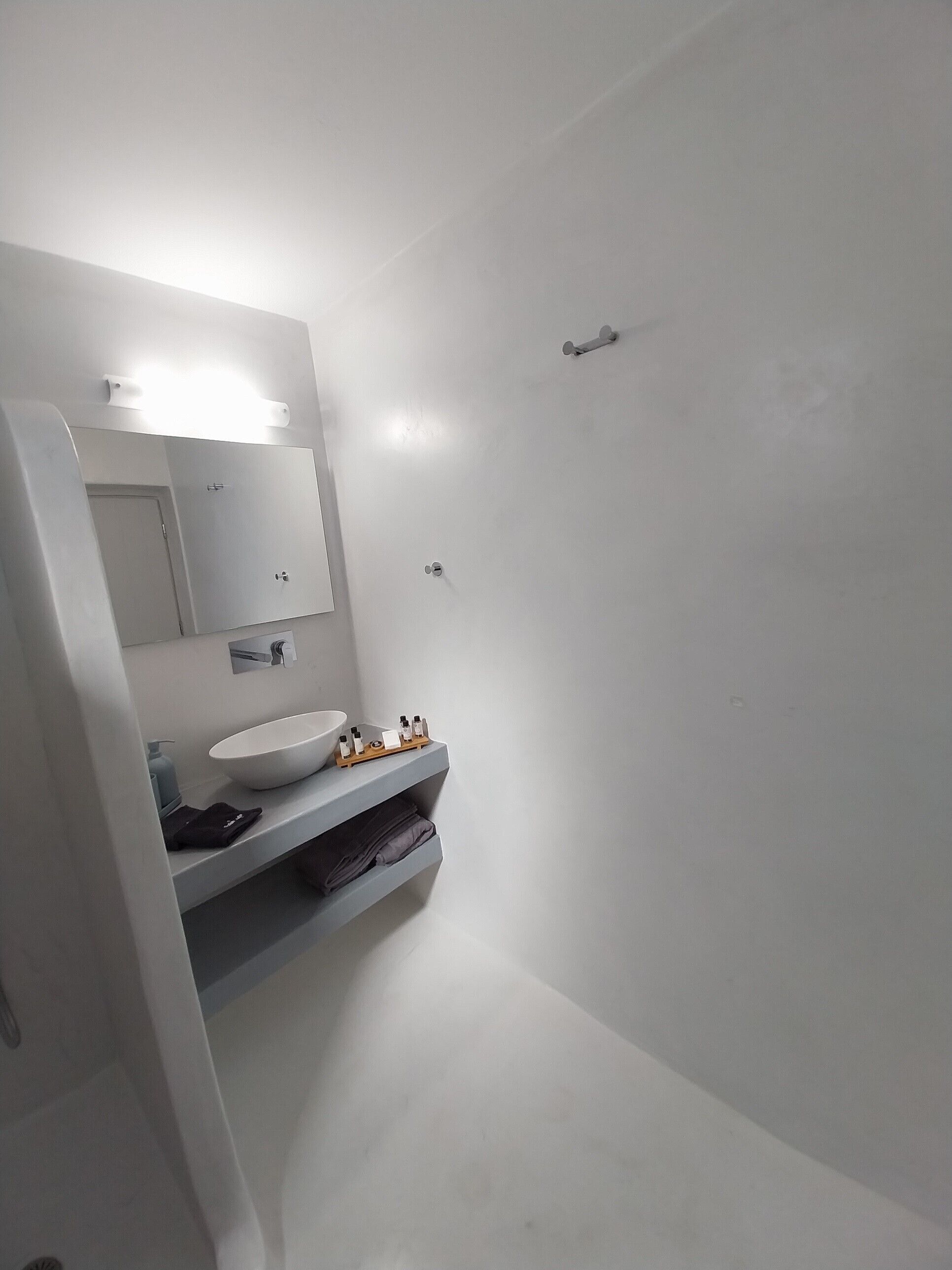 A modern bathroom with a white sink, mirror, and a shower area.