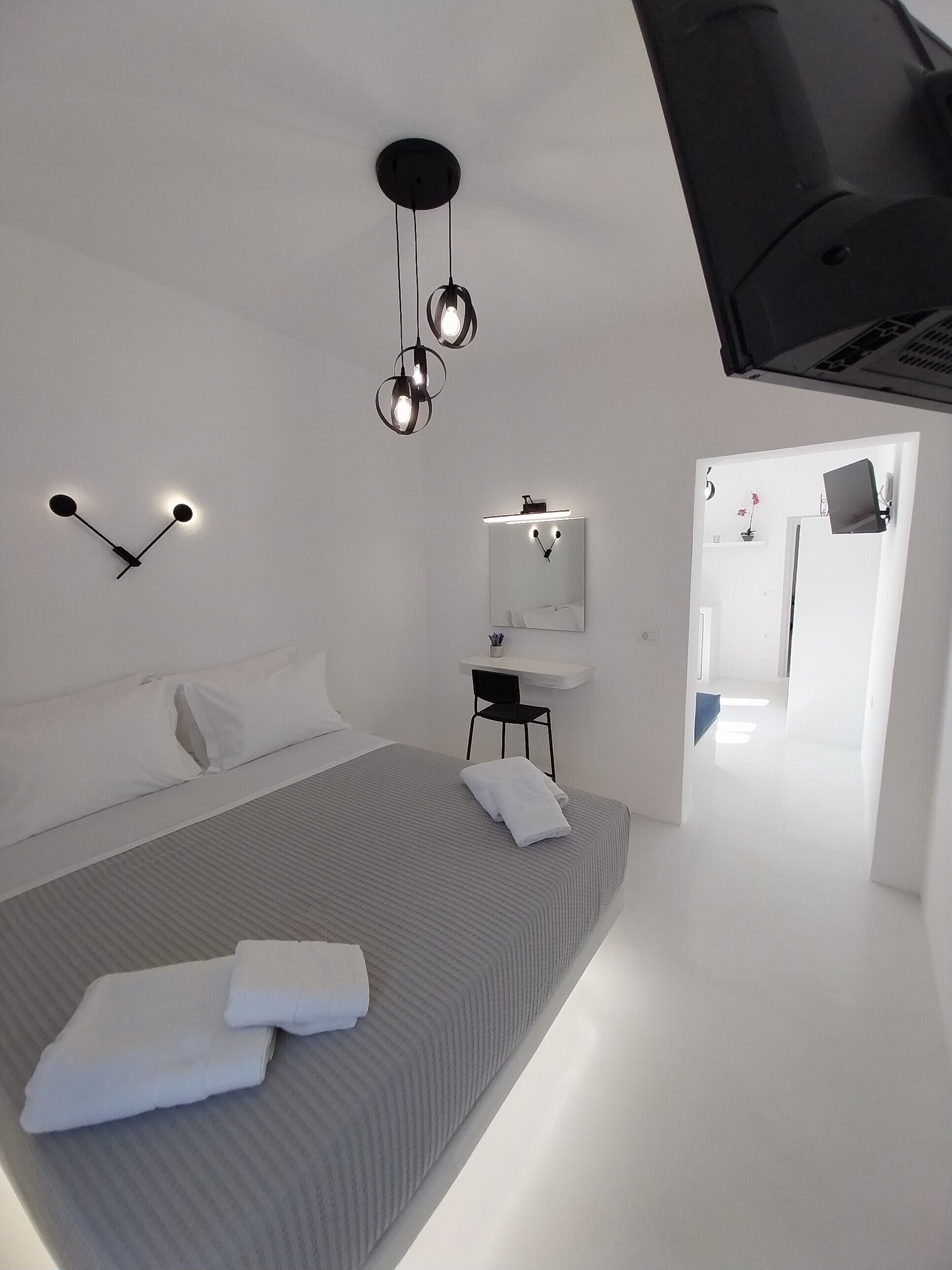 A modern bedroom with a large bed, bedside tables, a mirror, and a ceiling light fixture.