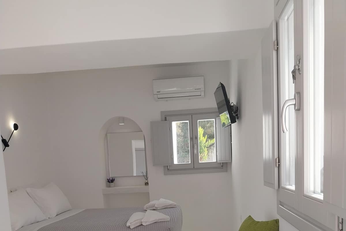 Ein modernes Schlafzimmer mit einem Bett, einer Couch, einem Fenster und einer Klimaanlage.
