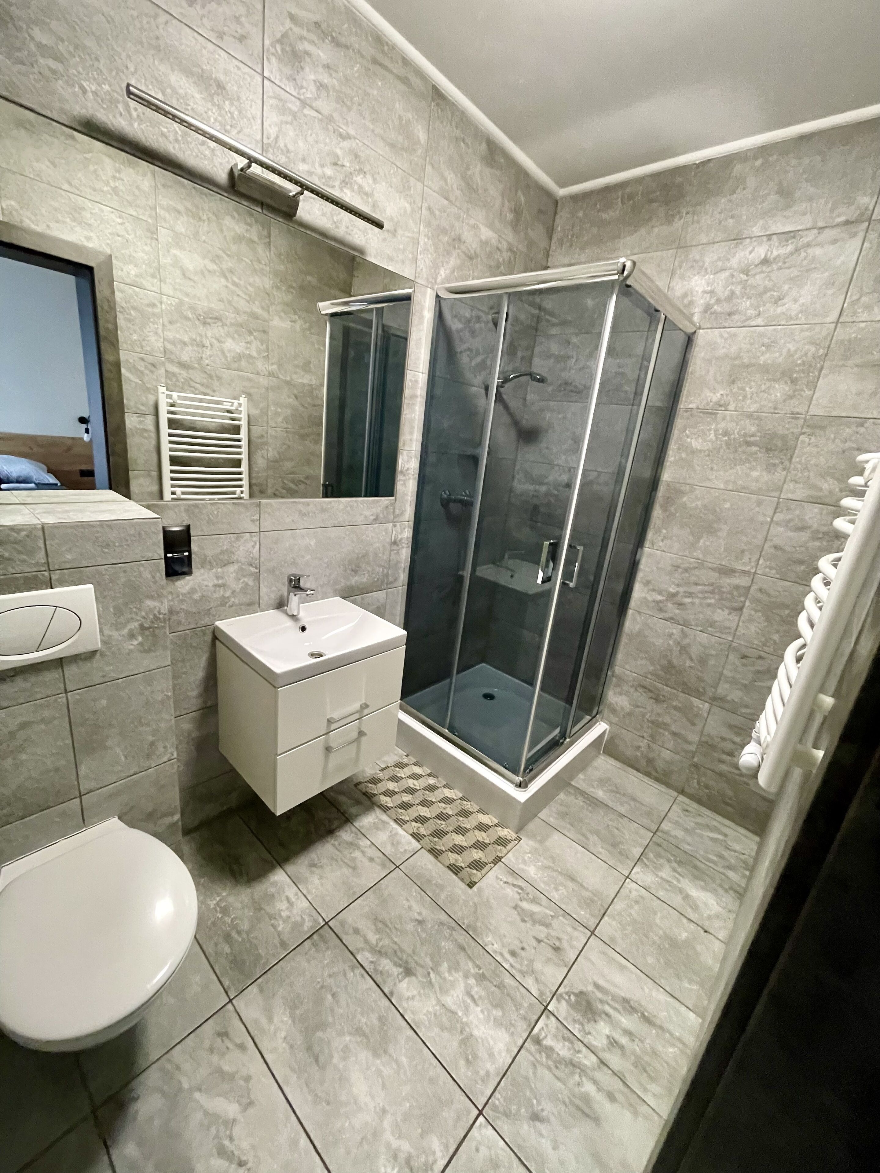 A modern bathroom with a glass-enclosed shower, a white sink, and a toilet.