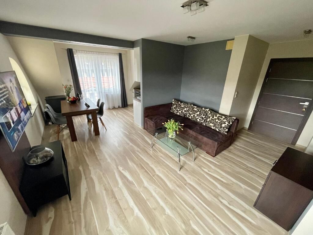 A modern living room with a sofa, glass coffee table, and a dining area with a table and chairs.
