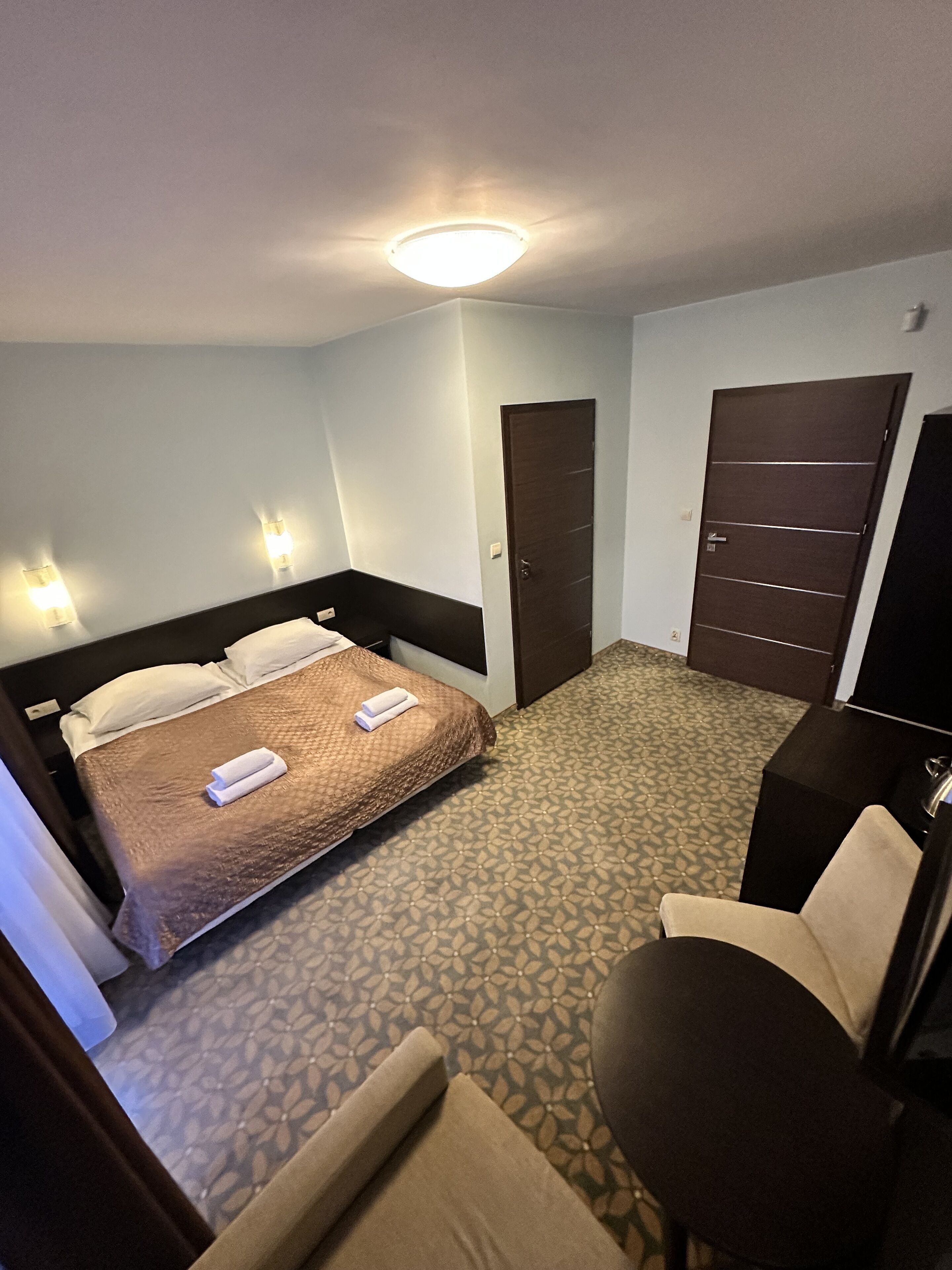 A hotel room with a bed, a desk, and a chair.