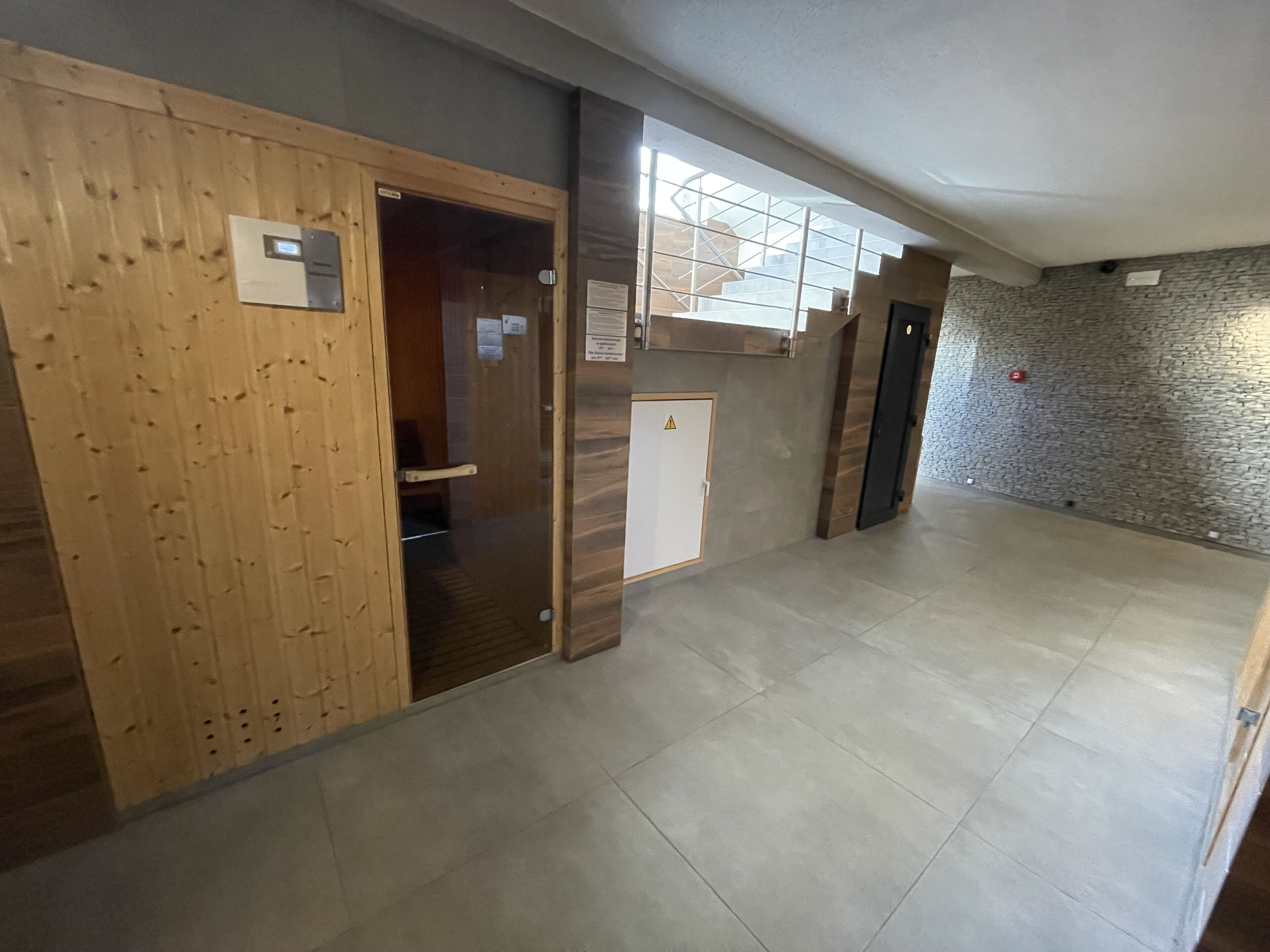 Un pasillo con una puerta de madera, un armario pequeño blanco y una pared de piedra.