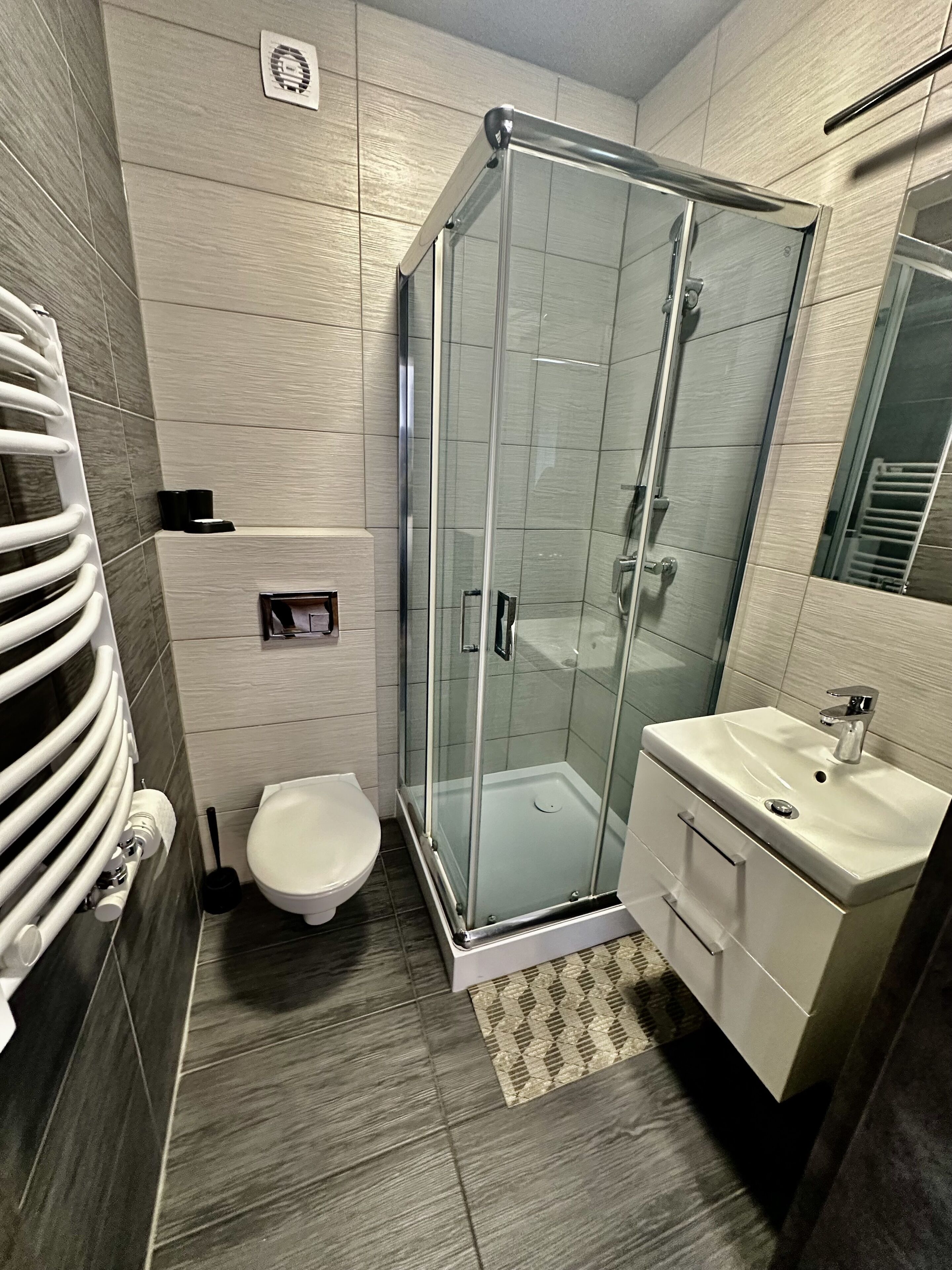 A modern bathroom with a glass-enclosed shower, a toilet, and a sink.