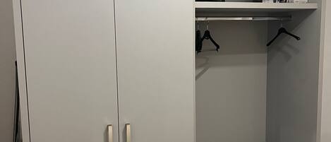 Un armari gris amb dues portes, una prestatgeria i zona penjant.