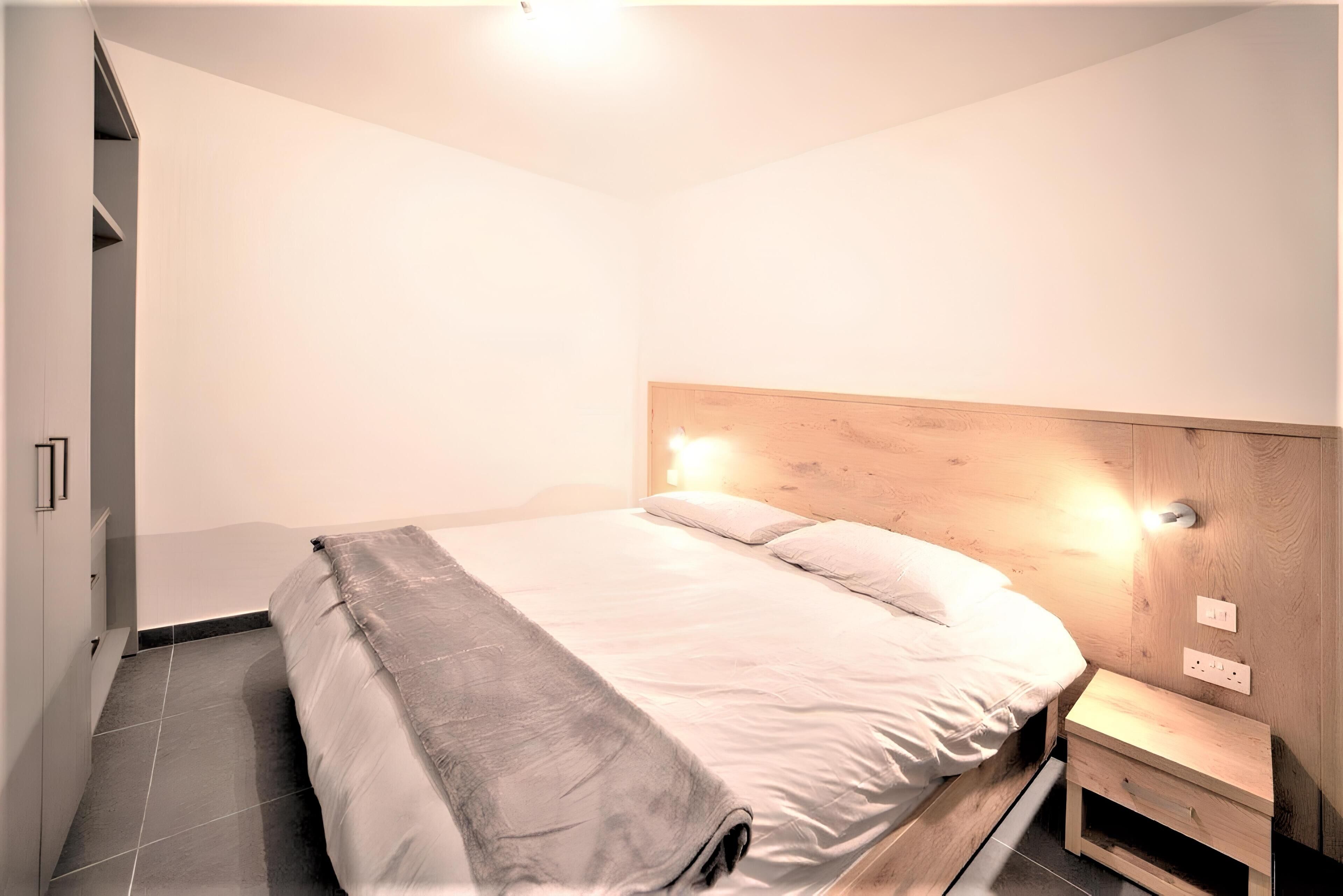 Un dormitorio moderno con cama, mesita de noche y mesita auxiliar empotrada.