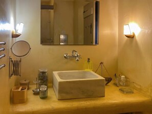 A bathroom with a large mirror, a sink, and various toiletries on the counter.