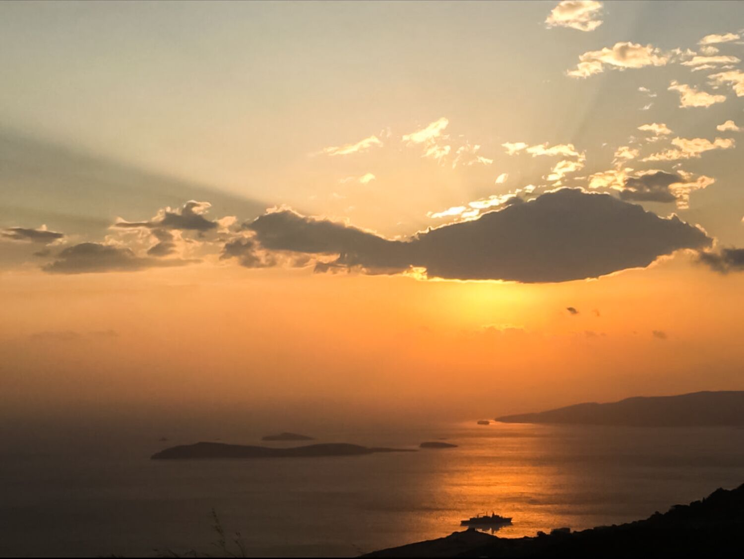 A sunset over a calm sea with distant landforms.