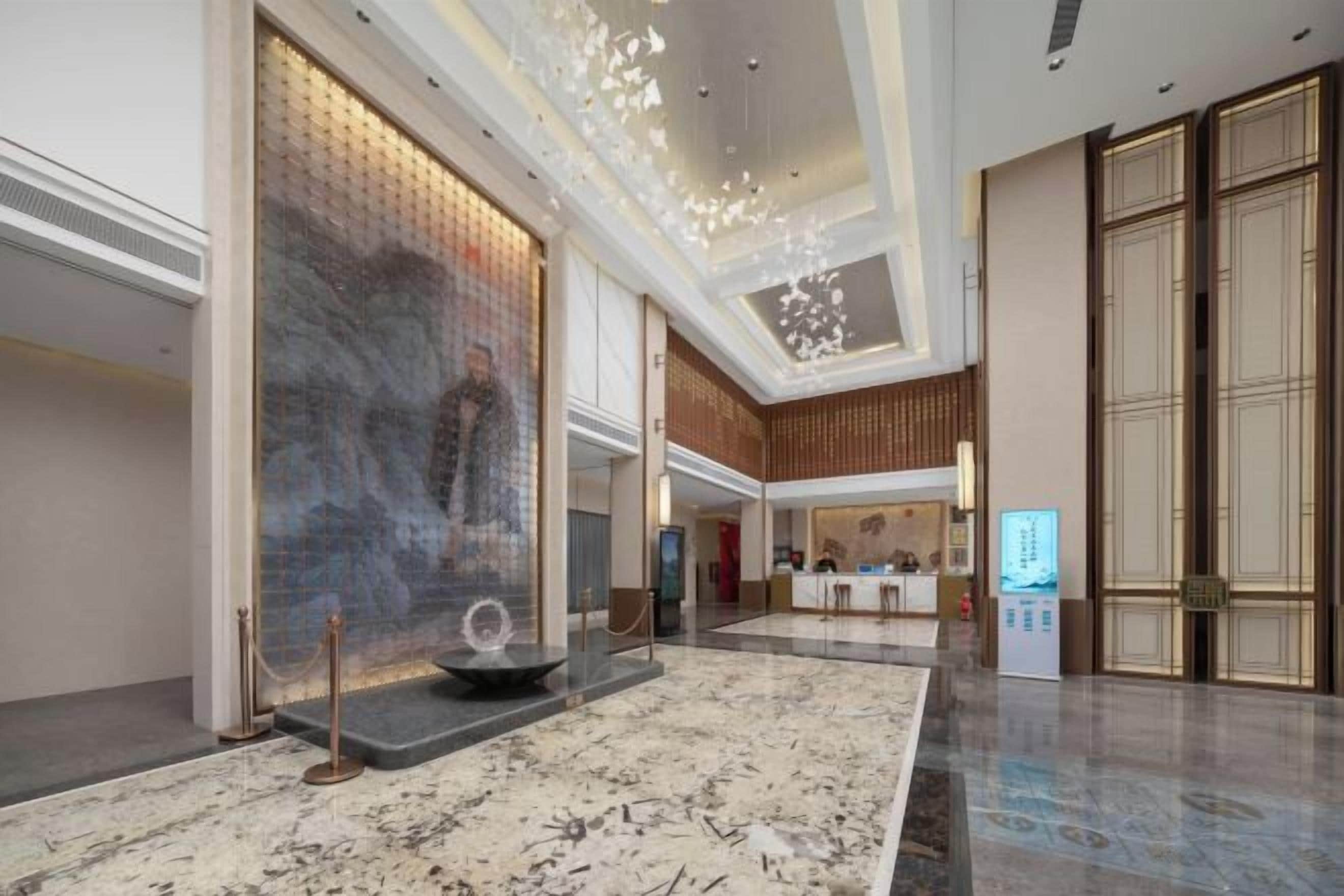 A spacious lobby with a marble floor, a large wall art piece, and a reception desk.