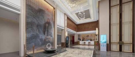 A spacious lobby with a marble floor, a large wall art piece, and a reception desk.