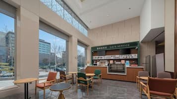 A modern cafe with a counter, seating area, and large windows.