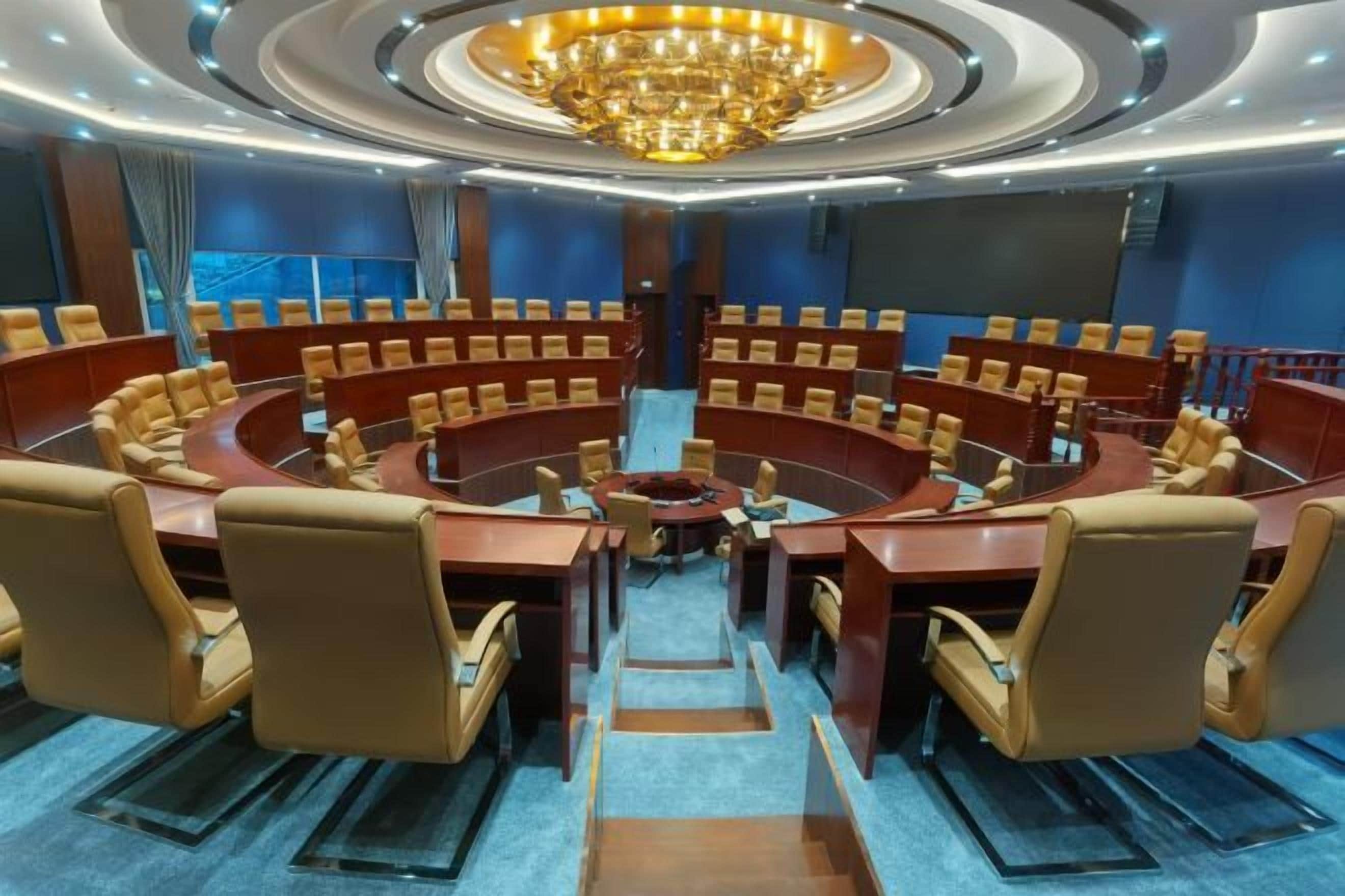 A conference room with a circular table, multiple chairs, and a chandelier.