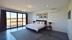 A bedroom with a large bed, a view through a sliding door, and a ceiling fan. - Off The Hook Kalbarri  (Kalbarri)