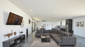 A spacious living room with a large sectional sofa, a coffee table, and a flat-screen TV mounted on the wall. - Off The Hook Kalbarri  (Kalbarri)