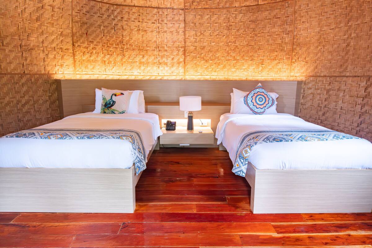 A room with two beds, a nightstand, and a lamp.