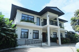 A two-story house with a balcony, large windows, and a garden area.