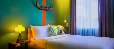 A bed with white bedding, a lamp on a wooden nightstand, a decorative horn on the wall, and a window with curtains.
