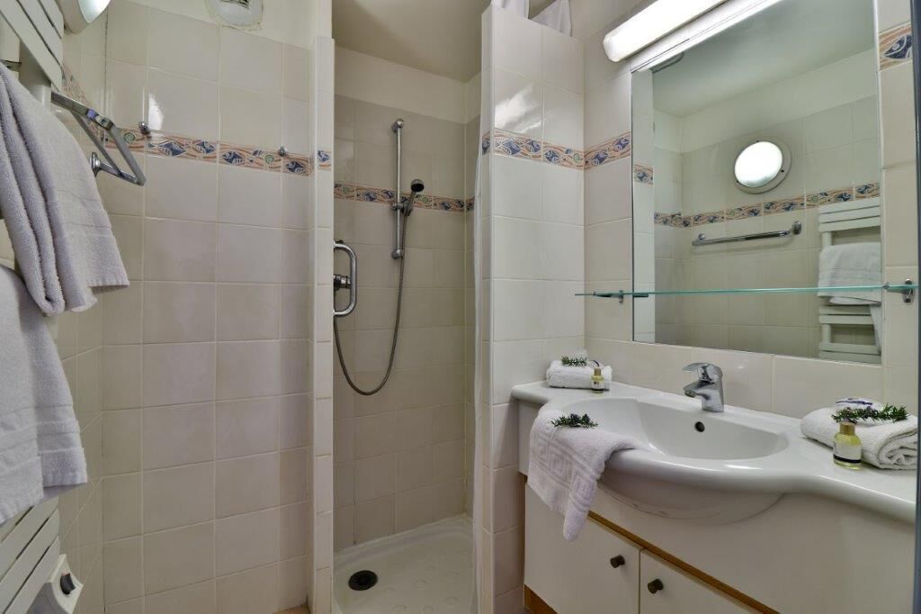 A bathroom with a shower, sink, and mirror.