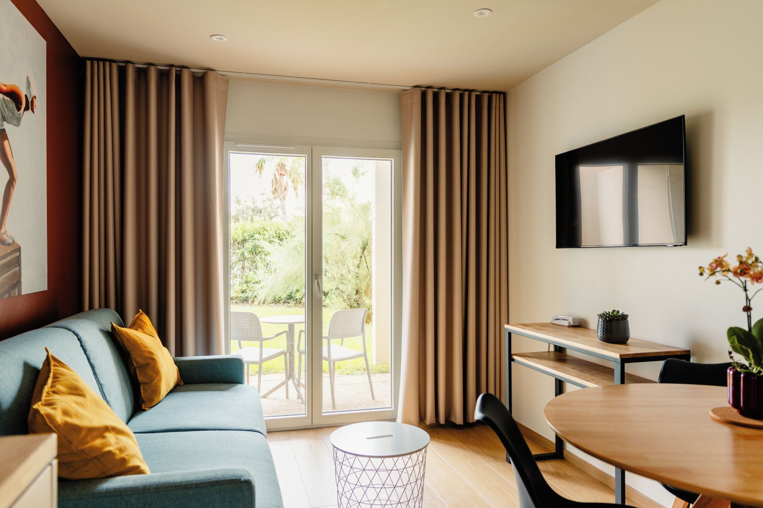 Een moderne woonkamer met een bank, een eettafel en een aan de muur bevestigde televisie.