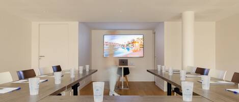 A conference room with a long table, chairs, a projector screen, and a laptop.