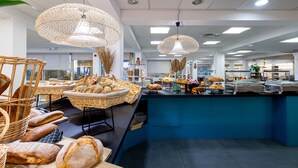 A buffet area with various breads and pastries displayed in baskets and on a counter. - Kaliopé Hotel & Résidence by Oustal del Mar (Le Lavandou)