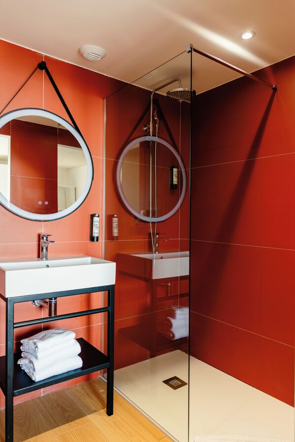 A modern bathroom with a glass-enclosed shower, a round mirror, and a white sink. - Kaliopé Hotel & Résidence by Oustal del Mar (Le Lavandou)