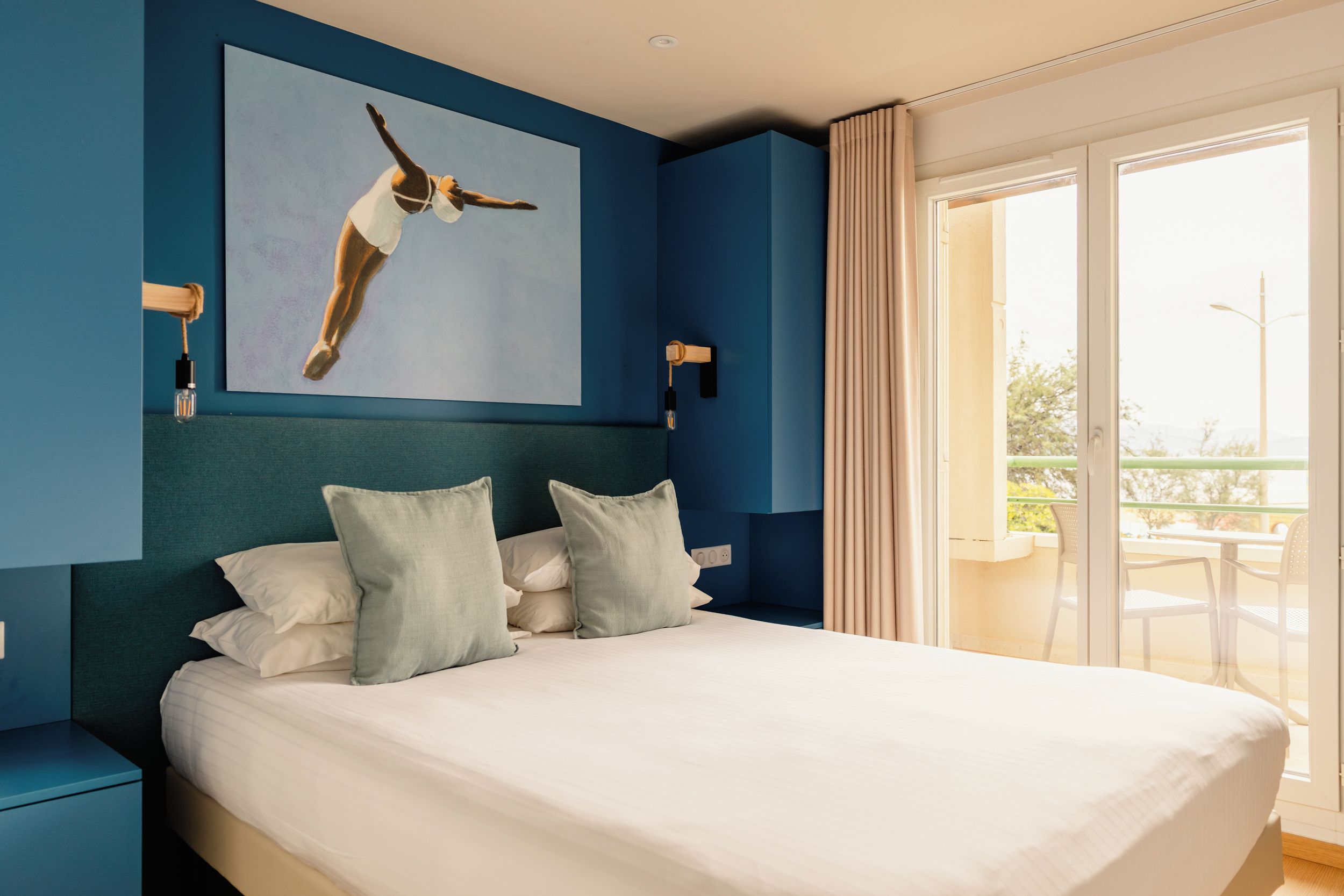 Une chambre à coucher moderne avec un grand lit, un tableau représentant un oiseau et une vue sur l’extérieur.