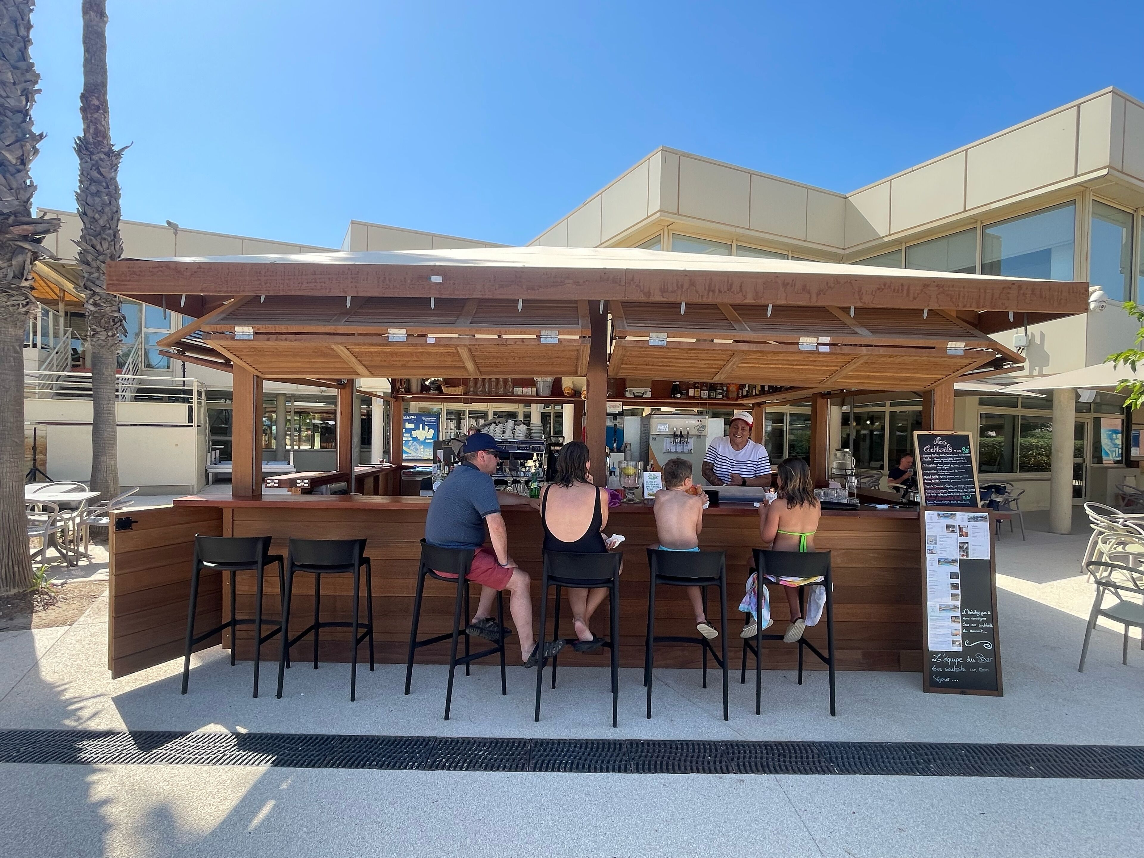 Un espace bar extérieur avec des sièges en bois et un comptoir.