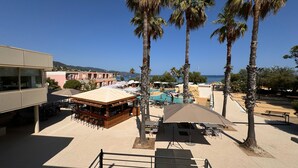 A resort with outdoor seating, palm trees, and a pool area. - Kaliopé Hotel & Résidence by Oustal del Mar (Le Lavandou)