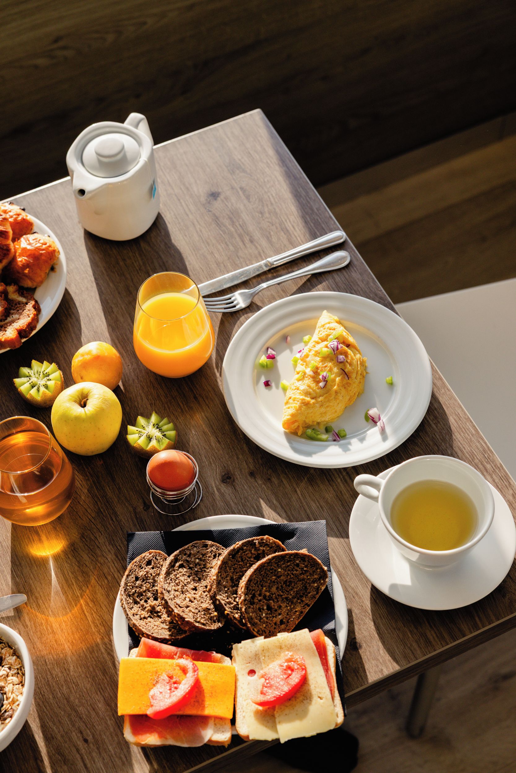 Une table de petit-déjeuner avec divers aliments, une théière et une tasse de thé.