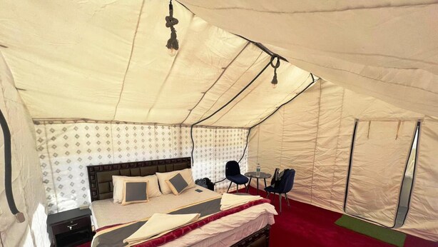 A tented room with a bed, two chairs, a small table, and a nightstand. - Himalayan Hideout (Leh)