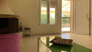 Ein Zimmer mit Kamin, einem Tisch mit Keksen, einem Fenster mit Jalousien und einer Tür, die nach draußen führt.