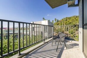 A balcony with a metal railing, a table, and two chairs. - Hills Valleys (Puli)