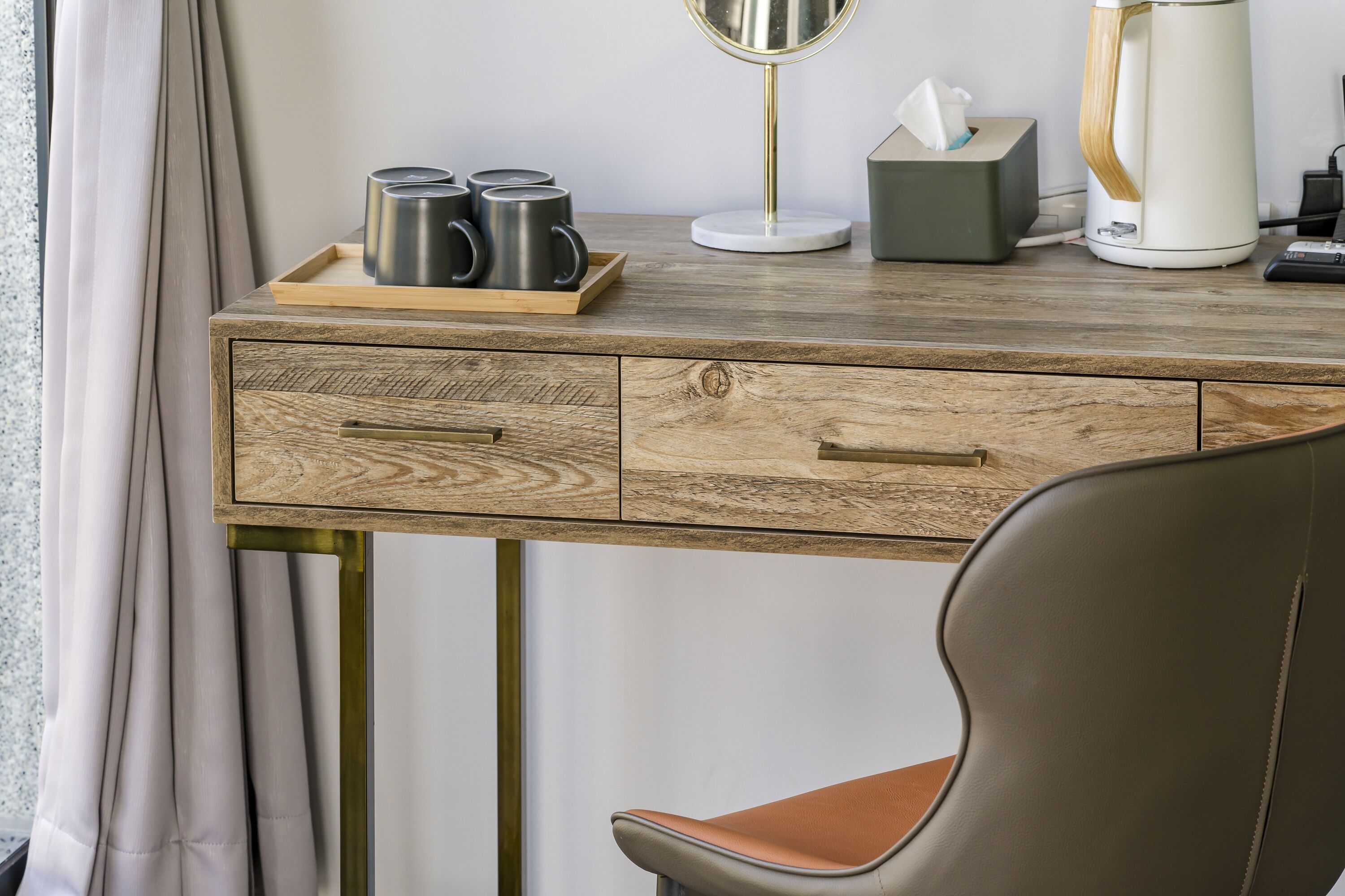 A wooden desk with a tray holding mugs, a tissue box, and a coffee maker.