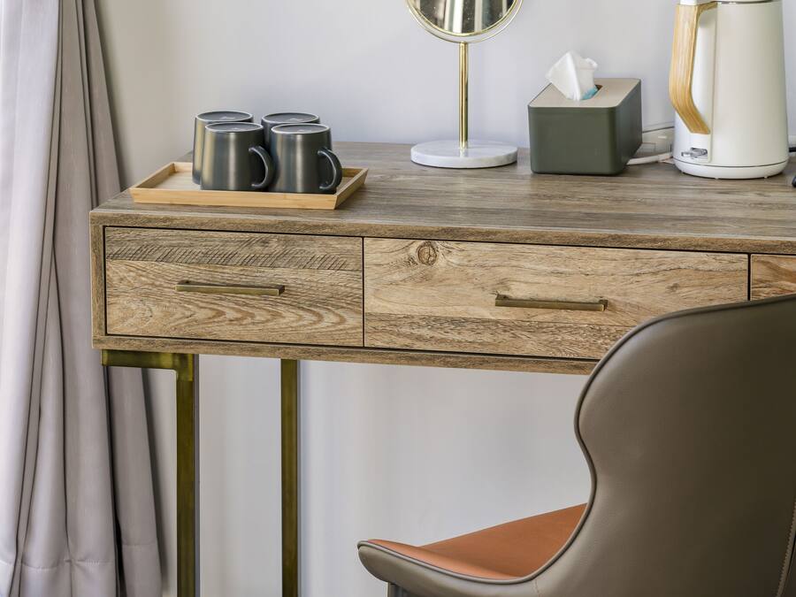 A wooden desk with a tray holding mugs, a tissue box, and a coffee maker.
