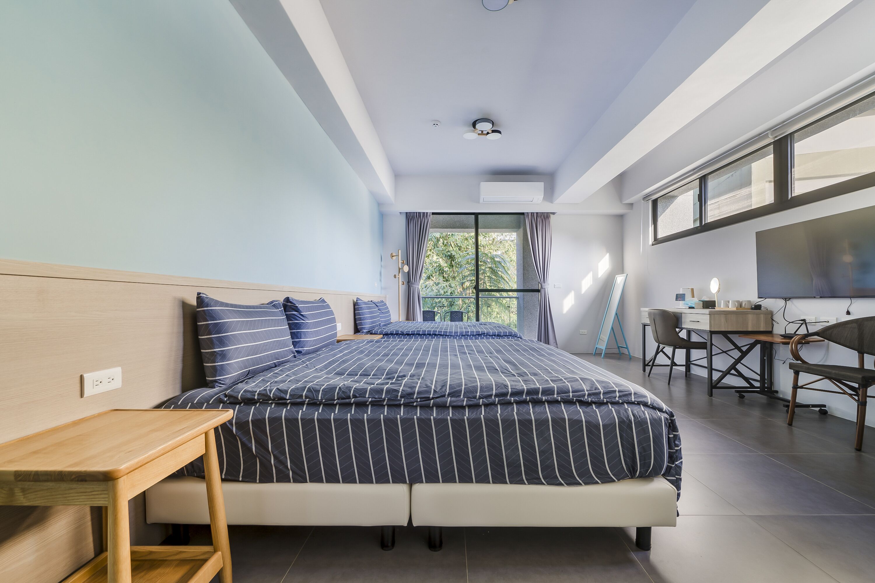 A modern bedroom with a bed, a desk, and a window.