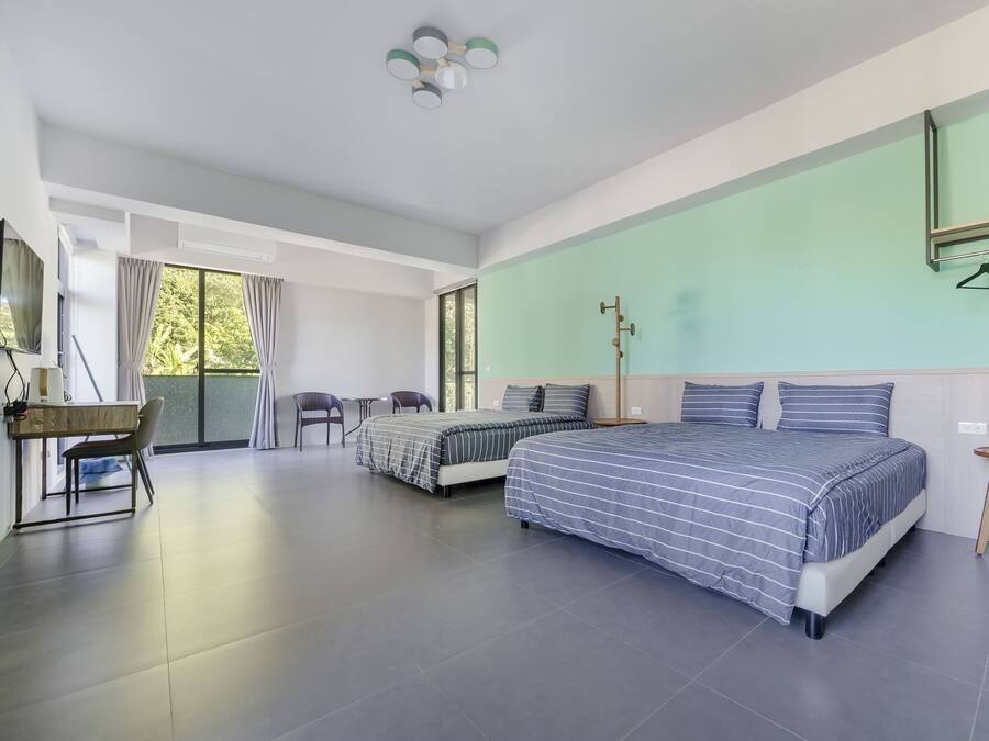 A modern hotel room with two beds, a desk, and a chair.