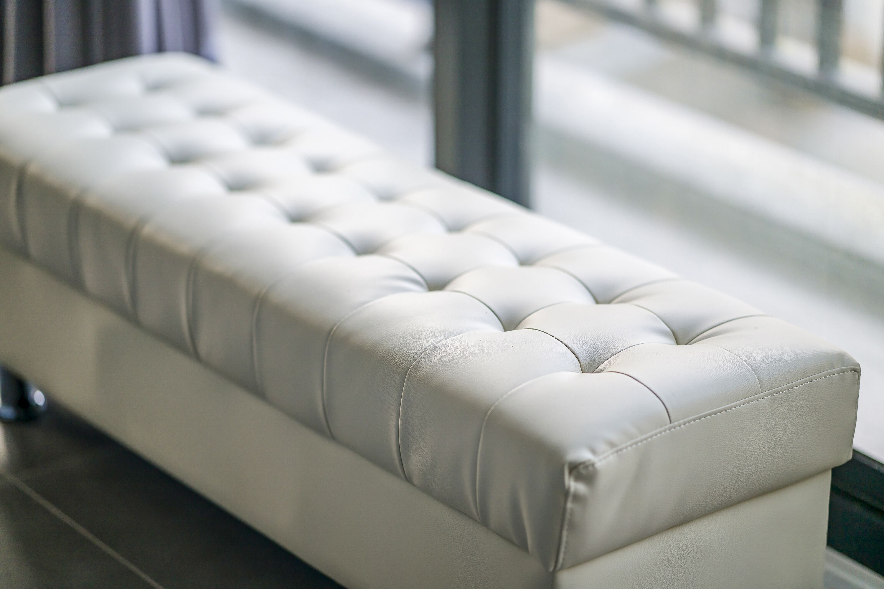 Un banc blanc, doté d’un dossier arrondi et d’une assise lisse et légèrement capitonnée.